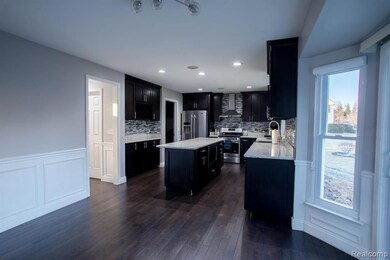Kitchen with dark cabinets, tasteful backsplash, a kitchen island, appliances with stainless steel finishes, and wall chimney range hood