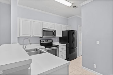 Kitchen featuring ornamental molding, appliances with stainless steel finishes, light countertops, white cabinetry, and a textured ceiling