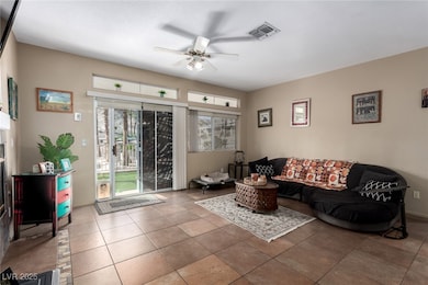 Living room featuring a ceiling fan, tile patterned floors, and a fireplace