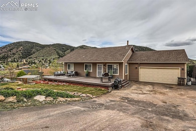 Ranch-style home featuring an attached garage, concrete driveway, a deck with mountain view, and roof with shingles