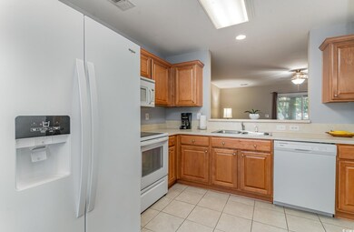 Kitchen featuring white appliances, ceiling fan, l