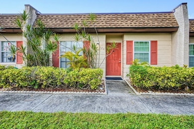 Doorway to property with a shingled roof, stucco siding, and mansard roof