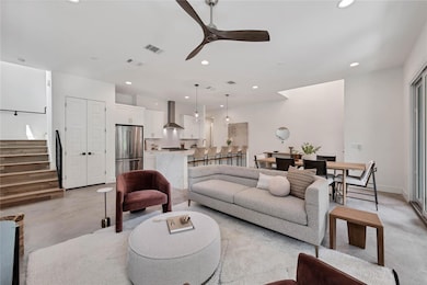 Living area featuring a ceiling fan, finished concrete flooring, recessed lighting, and stairs