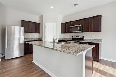 Kitchen with dark brown cabinetry, a sink, stainle