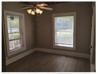 Unfurnished room featuring dark wood-type flooring and a ceiling fan