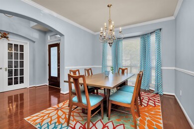 This is another view of the formal dining area featuring bay window, wood floors, chair molding, crown molding and gorgeous, wide arched entry.