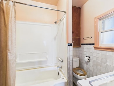 Bathroom featuring shower / bathtub combination with curtain, tile walls, a wainscoted wall, and vanity