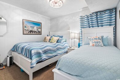 Bedroom with carpet floors, ornamental molding, and a textured ceiling