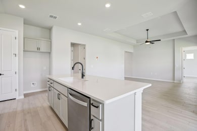 Kitchen with light wood finished floors, stainless steel dishwasher, open floor plan, recessed lighting, and a kitchen island with sink