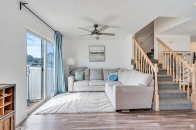 Living area with wood finished floors, stairway, and a ceiling fan