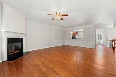 Living room with a ceiling fan, a fireplace, a chandelier, a decorative wall, and light wood-style floors