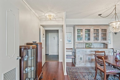 Dining area featuring a textured ceiling, dark wood-style floors, and crown molding