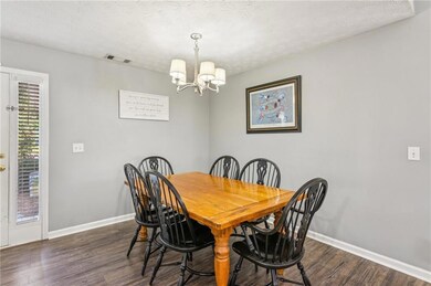 Dining area with a chandelier, dark wood finished floors, and a textured ceiling