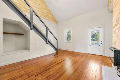 Foyer featuring hardwood / wood-style flooring, high vaulted ceiling, and stairway