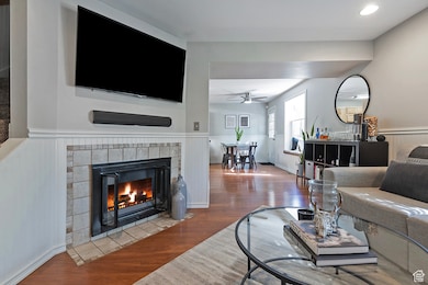 Living area with wainscoting, wood finished floors, and a tile fireplace