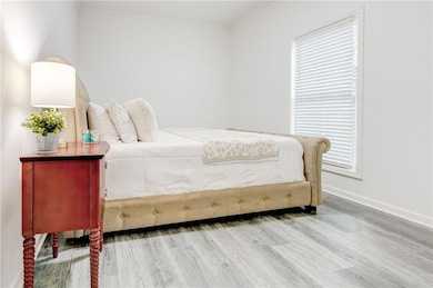 Downstairs bedroom featuring wood-type flooring and crown molding