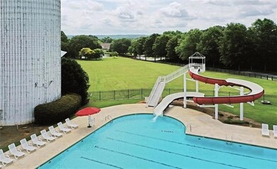 Community pool with a yard, fence, a water slide, 