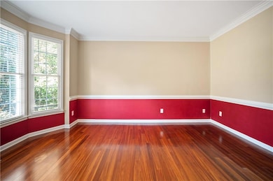 Empty room with crown molding and dark wood-type flooring