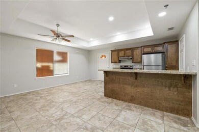 Kitchen featuring appliances with stainless steel finishes, a raised ceiling, a breakfast bar, and under cabinet range hood