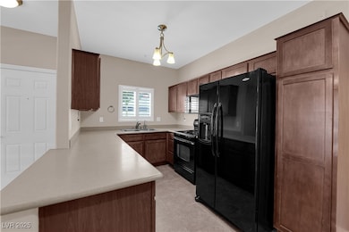 Kitchen featuring black appliances, light countert