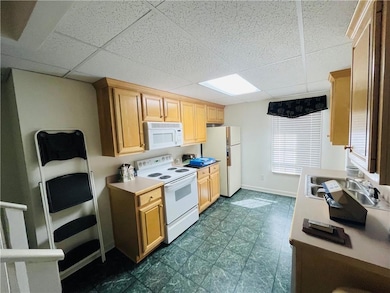 Kitchen with a sink, baseboards, white appliances,