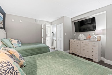 Bedroom with wood finished floors, baseboards, and ensuite bathroom