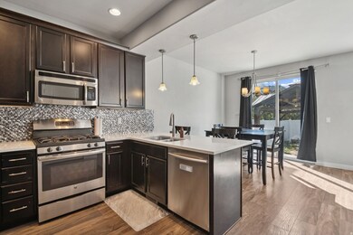 Kitchen featuring appliances with stainless steel finishes, a chandelier, dark wood finished floors, a peninsula, and recessed lighting