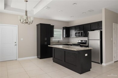 Kitchen with dark cabinets, a center island, stainless steel appliances, decorative light fixtures, and visible vents