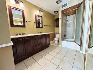 Bathroom featuring light tile patterned floors, enclosed tub / shower combo, and double vanity