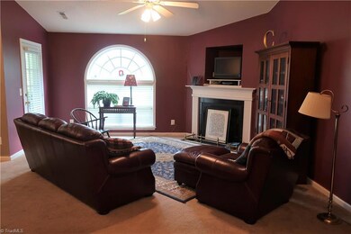 Spacious living room with arched window, fireplace w/gas logs, and vaulted ceiling