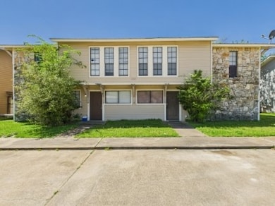 View of property with a front yard and stone sidin