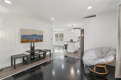 Living area with recessed lighting, dark wood-type flooring, and crown molding