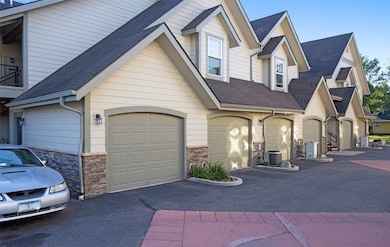View of front facade featuring a shingled roof, stone siding, and driveway