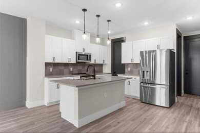 Kitchen featuring a kitchen island with sink, tasteful backsplash, light hardwood / wood-style flooring, and appliances with stainless steel finishes