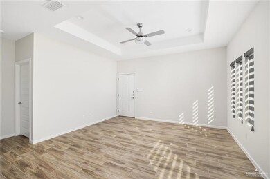 Spare room featuring a raised ceiling, visible vents, ceiling fan, and wood finished floors