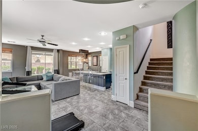 Living area featuring stairs, a ceiling fan, baseb