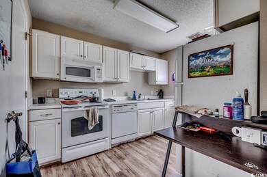 Kitchen featuring a textured ceiling, light hardwo