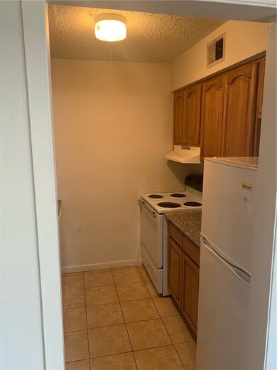 Kitchen featuring ventilation hood, a textured cei