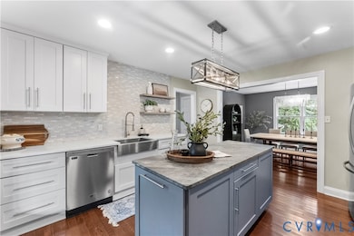 Kitchen with pendant lighting, backsplash, appliances with stainless steel finishes, dark wood-type flooring, and recessed lighting