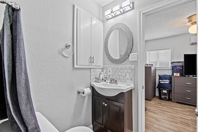 Bathroom with a textured wall, wood finished floo