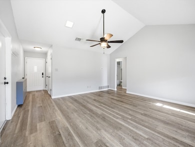 Unfurnished living room featuring light wood finished floors, a ceiling fan, and high vaulted ceiling
