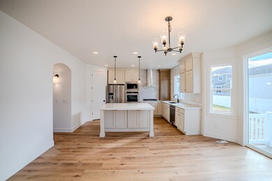 Kitchen with backsplash, a center island, light wood-style floors, arched walkways, and recessed lighting