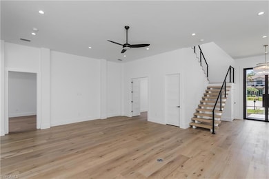 Unfurnished living room featuring stairway, a ceiling fan, recessed lighting, light wood-style floors, and baseboards