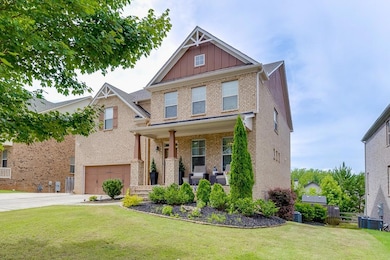 Craftsman-style house featuring board and batten siding, brick siding, a porch, driveway, and a front yard