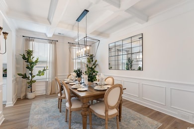 Dining area featuring coffered ceiling, beamed ceiling, a chandelier, a decorative wall, and wood finished floors