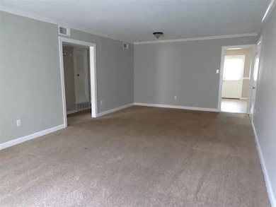 Carpeted empty room with ornamental molding and ba