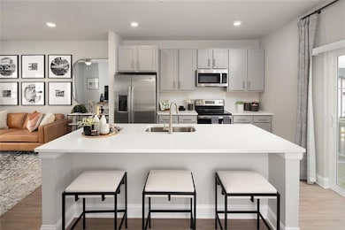 Kitchen with stainless steel appliances, gray cabinets, tasteful backsplash, light wood finished floors, and recessed lighting