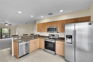 Kitchen with appliances with stainless steel finishes, recessed lighting, open floor plan, light tile patterned flooring, and dark stone counters