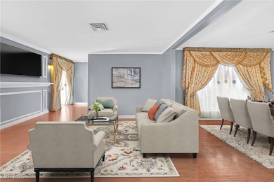 Living area with wood finished floors, crown moldi