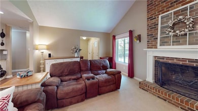 Living area featuring carpet, vaulted ceiling, and a fireplace